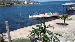 A boat docked at a pier with a small beach area and a few houses in the background.