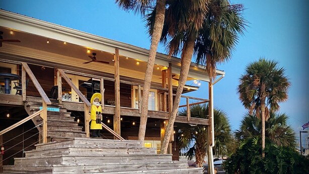 A multi-story building with wooden exterior and a staircase leading to the entrance.