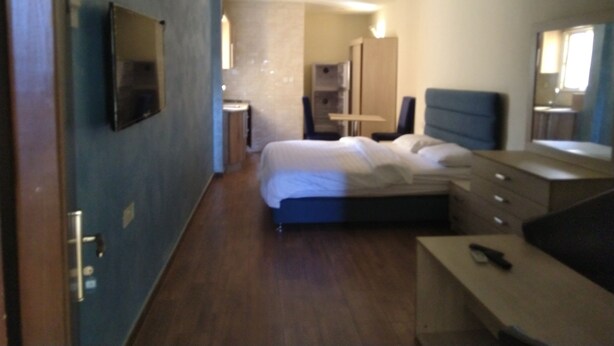 A hotel room with a bed, bedside table, dresser, and a mirror.