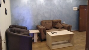 A room with a brown sofa, a small table, and a wooden cabinet.