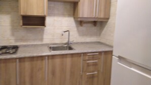A kitchen with wooden cabinets, a stainless steel sink, and a white refrigerator.