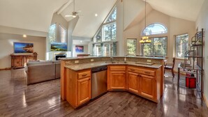 A spacious kitchen with a large island, wooden cabinets, and a high ceiling with skylights. - Sugar Pine Lodge: Hot Tub, Large Yard, Games (South Lake Tahoe)