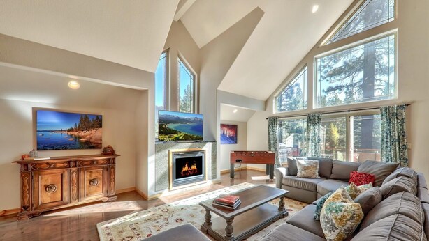 A spacious living room with a fireplace, large windows, and a cozy seating area. - Sugar Pine Lodge: Hot Tub, Large Yard, Games (South Lake Tahoe)