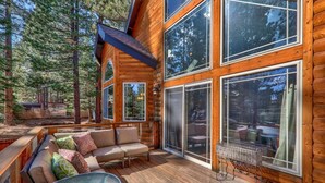 A log cabin with a deck, outdoor seating, and large windows. - Sugar Pine Lodge: Hot Tub, Large Yard, Games (South Lake Tahoe)