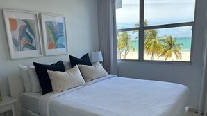 A bed with white bedding, a nightstand, and two framed artworks on the wall.
