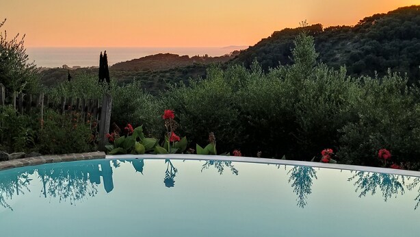 A swimming pool with a clear view of the surrounding landscape, including hills and a sunset. - Mastrogiannis villa Myrtia (Kavvadades)