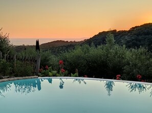 A swimming pool with a clear view of the surrounding landscape, including hills and a sunset. - Mastrogiannis villa Myrtia (Kavvadades)