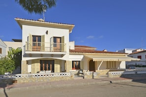 A two-story building with a balcony, a covered patio, and a stone wall.