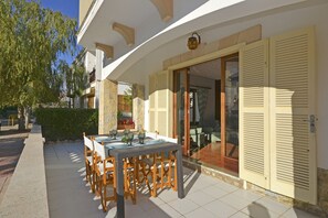 An outdoor dining area with a table set for four, surrounded by wooden chairs.