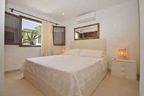 A bedroom with a bed, a nightstand, a mirror, and an air conditioning unit.
