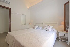 A bedroom with a large bed, two bedside tables, a mirror, and a wardrobe.