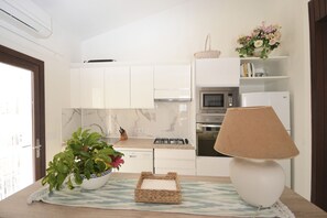 A modern kitchen with white cabinets, a Bosch gas stove, an LG microwave, and a white refrigerator.