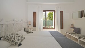 Een slaapkamer met een groot bed, een nachtkastje, een raam met gordijnen en uitzicht op groen.