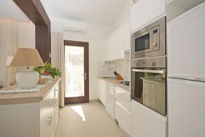A kitchen with white cabinets, a microwave, an oven, and a sink.