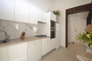 Eine moderne Küche mit weißen Schränken, einem Gasherd, einem Backofen und einem Kühlschrank.