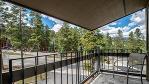 A balcony with a metal railing overlooking a parking area and a forested landscape. - Gold Camp Silver Strike Condo: On Shuttle Route (Breckenridge)
