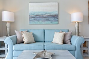Un canapé bleu clair avec deux coussins, un objet en forme d’étoile posé sur une table basse, et deux lampes de chaque côté.