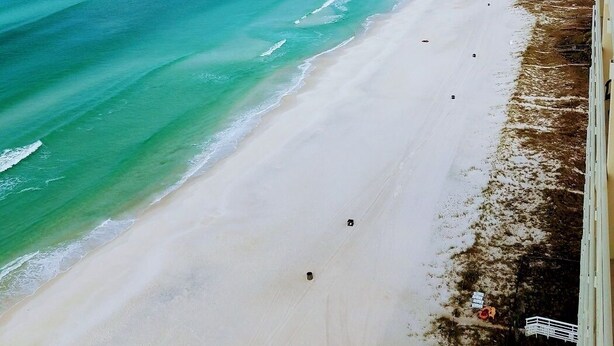 Une plage aux eaux turquoise et limpides, bordée d’un rivage sablonneux.