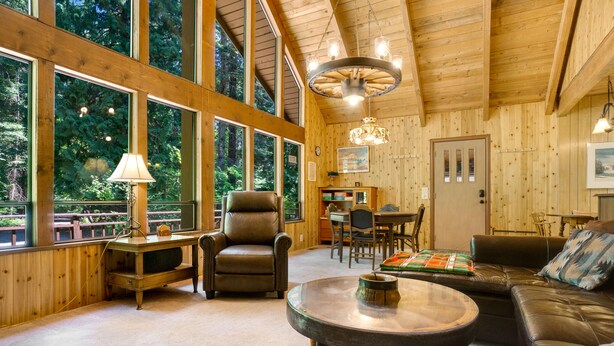L’intérieur chaleureux d’un chalet avec un canapé en cuir, une table basse ronde, un bureau en bois et un coin repas.