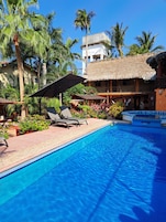 Una piscina al aire libre, sombrillas, sillones reclinables de piscina
