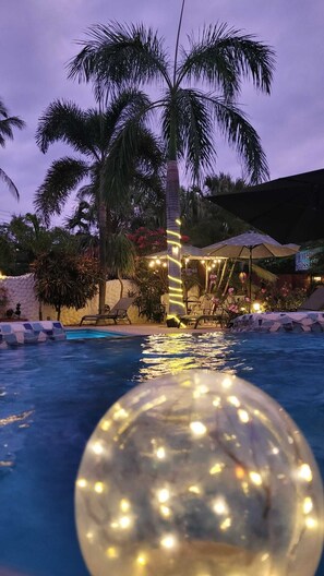 A swimming pool with palm trees, a clear sky, and a sign for 'Hotel Swiss.' - Hotelito Swiss Oasis - Adults Only (Puerto Escondido)