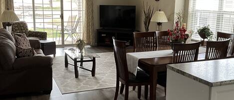 A spacious living room with a sofa, coffee table, TV, and dining area with chairs and a table.