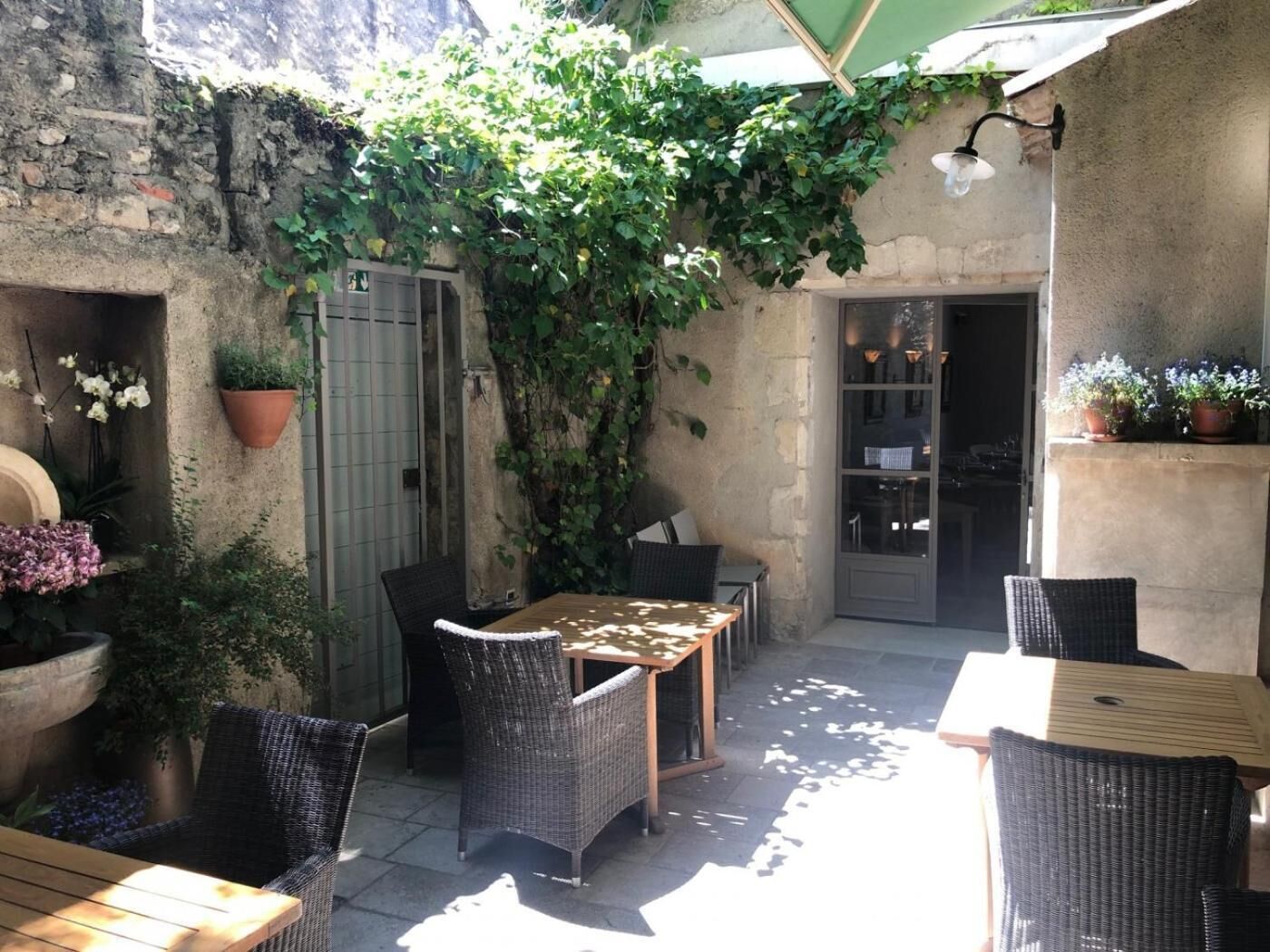Un patio al aire libre con mobiliario de mimbre, una mesa y una planta en maceta.
