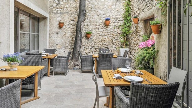 Una veranda esterna con pareti in pietra, mobili in vimini e piante in vaso.
