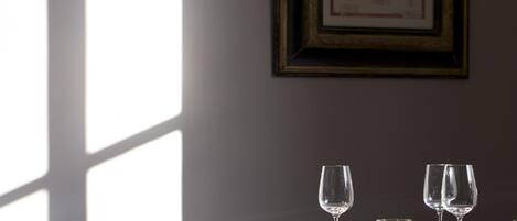 A dining table with wine glasses and a framed botanical illustration on the wall.