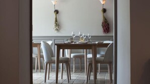 Zona pranzo con tavolo in legno apparecchiato per quattro persone, circondato da sedie.