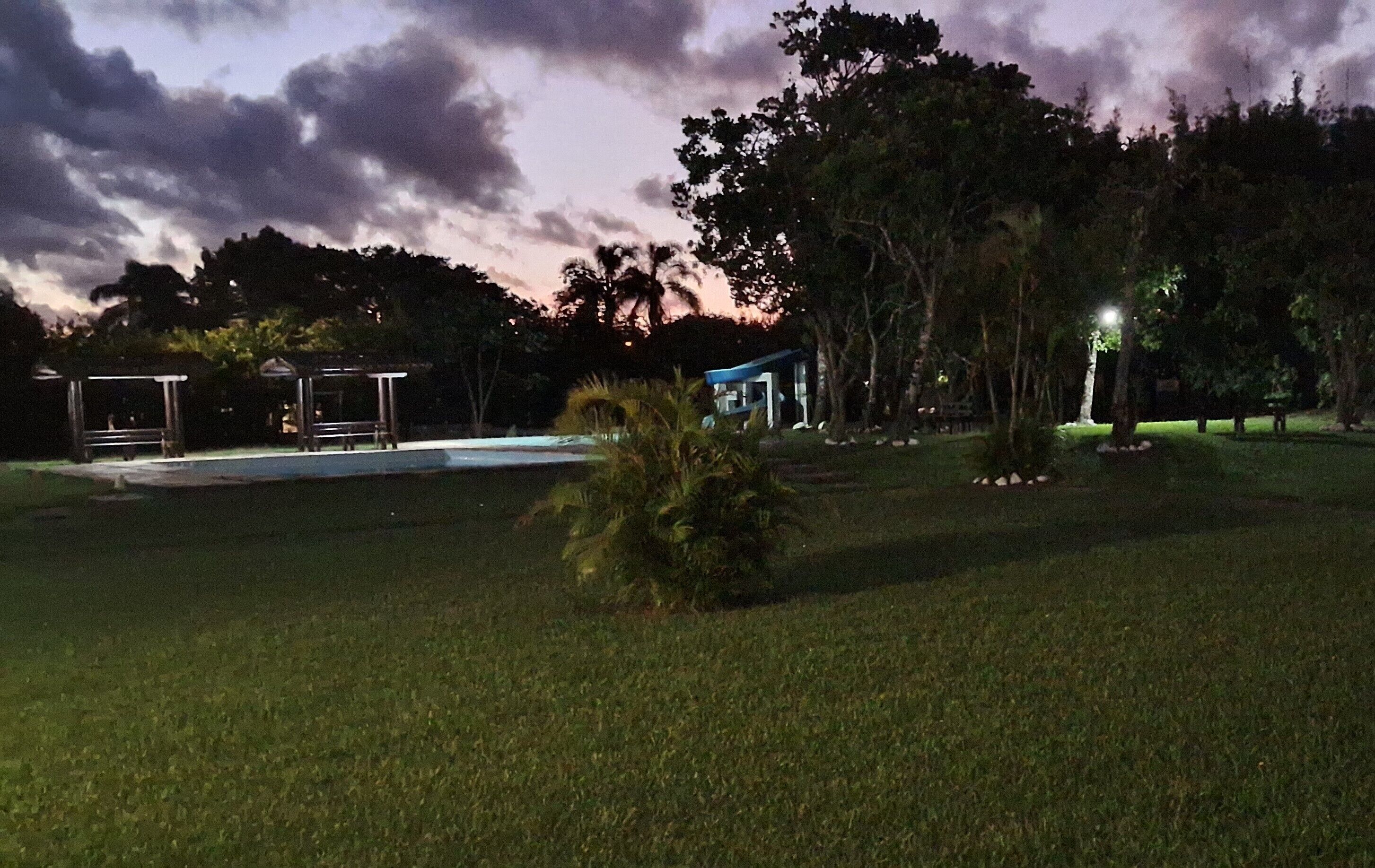 A nighttime view of a park with a pool, a gazebo, and a small building.