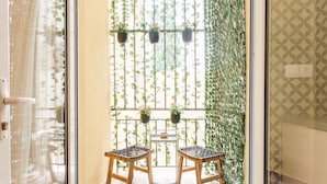 A room with two wicker chairs, a small table, and a view through a window with hanging plants. - Acropolis - historical attractions walking distance (Athina)