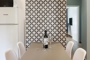 A dining area with a table set for two, a bottle of wine, and two glasses. A refrigerator is visible to the left. - Acropolis - historical attractions walking distance (Athina)