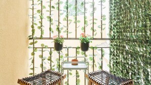 A balcony with two chairs, a small table, and hanging planters with flowers. - Acropolis - historical attractions walking distance (Athina)