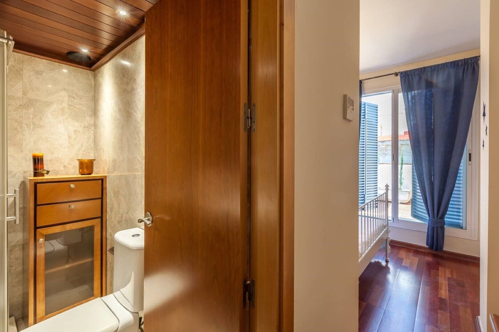A bathroom with a wooden cabinet, a toilet, and a shower area.