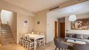 A modern apartment with a dining area, a living room, and a staircase. - Duplex penthouse with 70 m terrace (Sevilla)