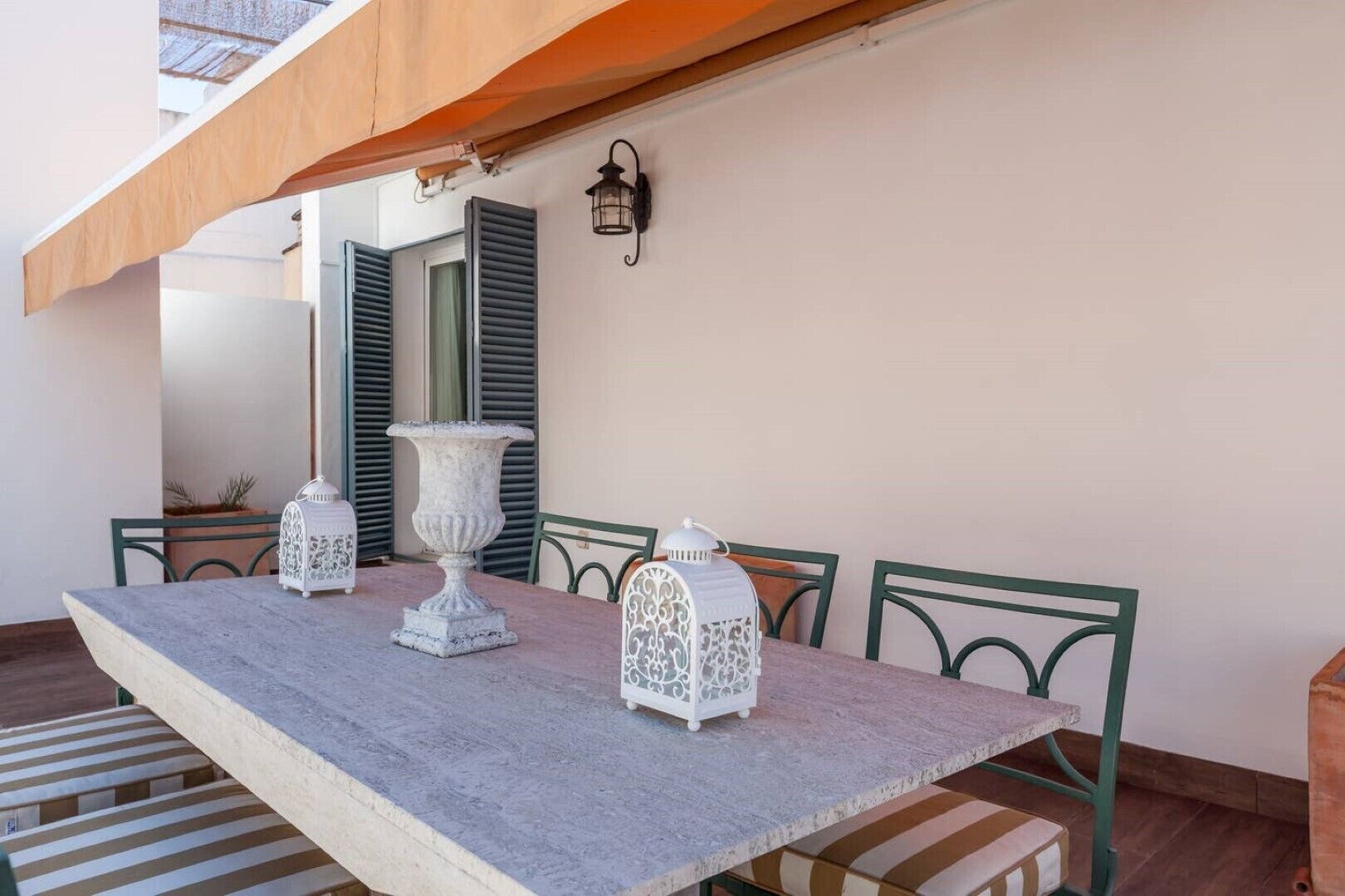 A dining area with a long table, white lanterns, and green chairs.