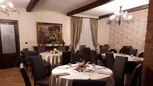 A dining area with round tables, black chairs, and chandeliers.