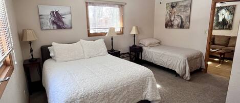 A bedroom with two beds, a ceiling fan, and artwork on the walls.