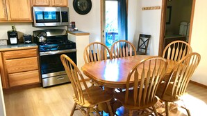 A kitchen with wooden cabinets, a microwave, a stove, and a dining table with chairs.