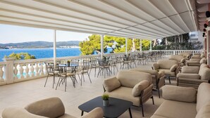 An outdoor seating area with tables and chairs, overlooking a body of water and hills. - Bellevue Maradiso Village by Aminess (Orebic)