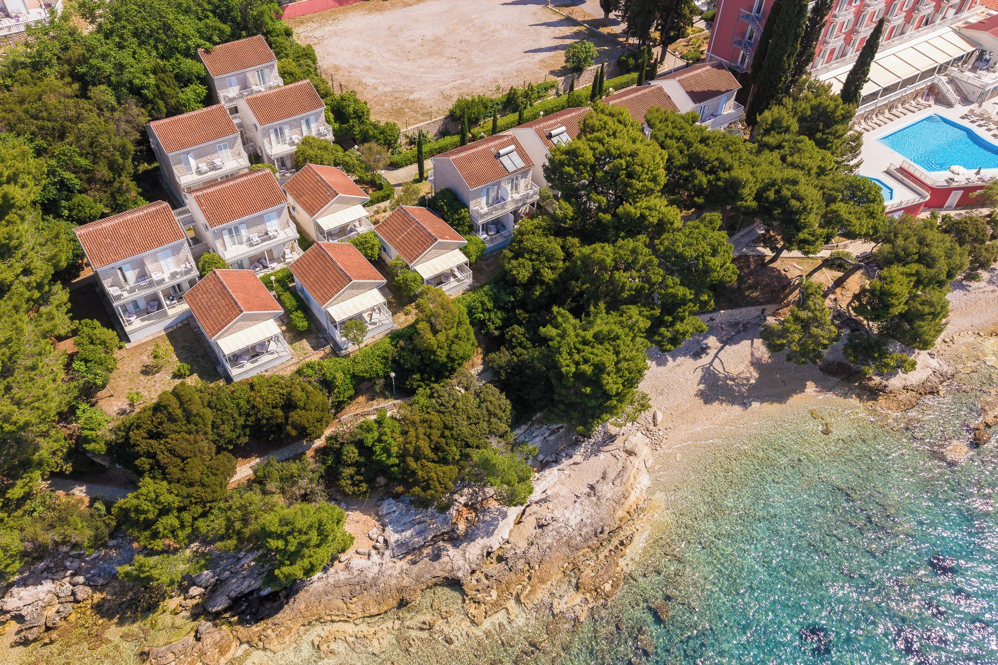 A coastal property with multiple villas, a beach, and a swimming pool.