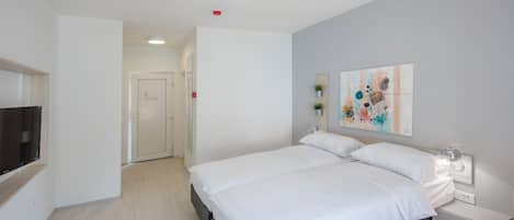 A modern bedroom with a large bed, bedside tables, a flat-screen TV, and a painting on the wall.