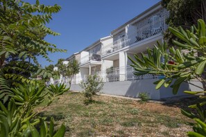 A multi-story building with balconies, surrounded by greenery and a clear sky. - Bellevue Maradiso Village by Aminess (Orebic)