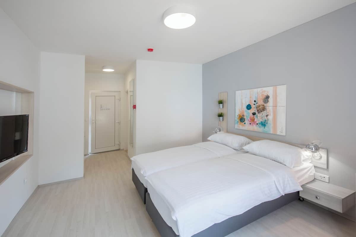 A modern bedroom with a large bed, bedside tables, a flat-screen TV, and a painting on the wall.