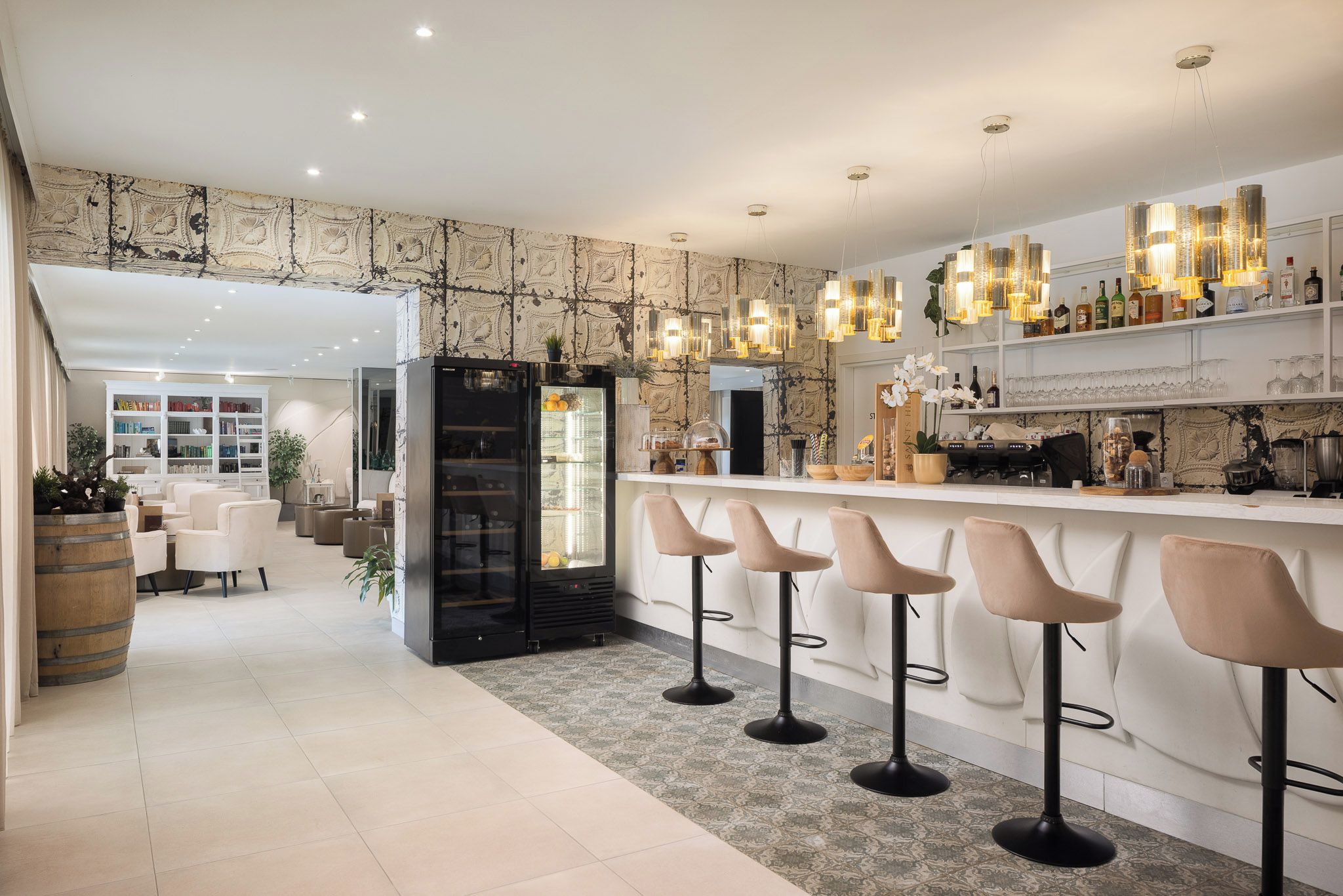 A modern kitchen with a bar area, bar stools, and a refrigerator.