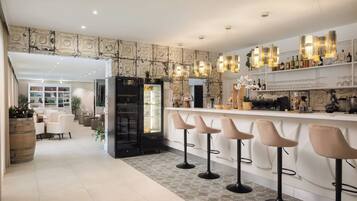 A modern kitchen with a bar area, bar stools, and a refrigerator.