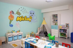 A children's playroom with a mural, storage units, a table with educational materials, and a bookshelf with toys. - Bellevue Maradiso Village by Aminess (Orebic)