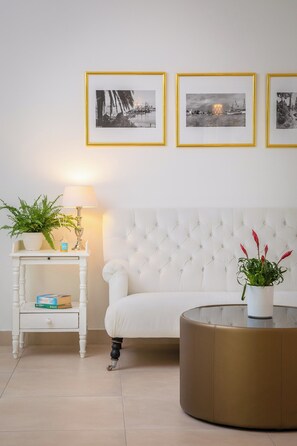 A living room with a white sofa, a round coffee table, a side table with a lamp, and three framed pictures on the wall. - Bellevue Maradiso Village by Aminess (Orebic)