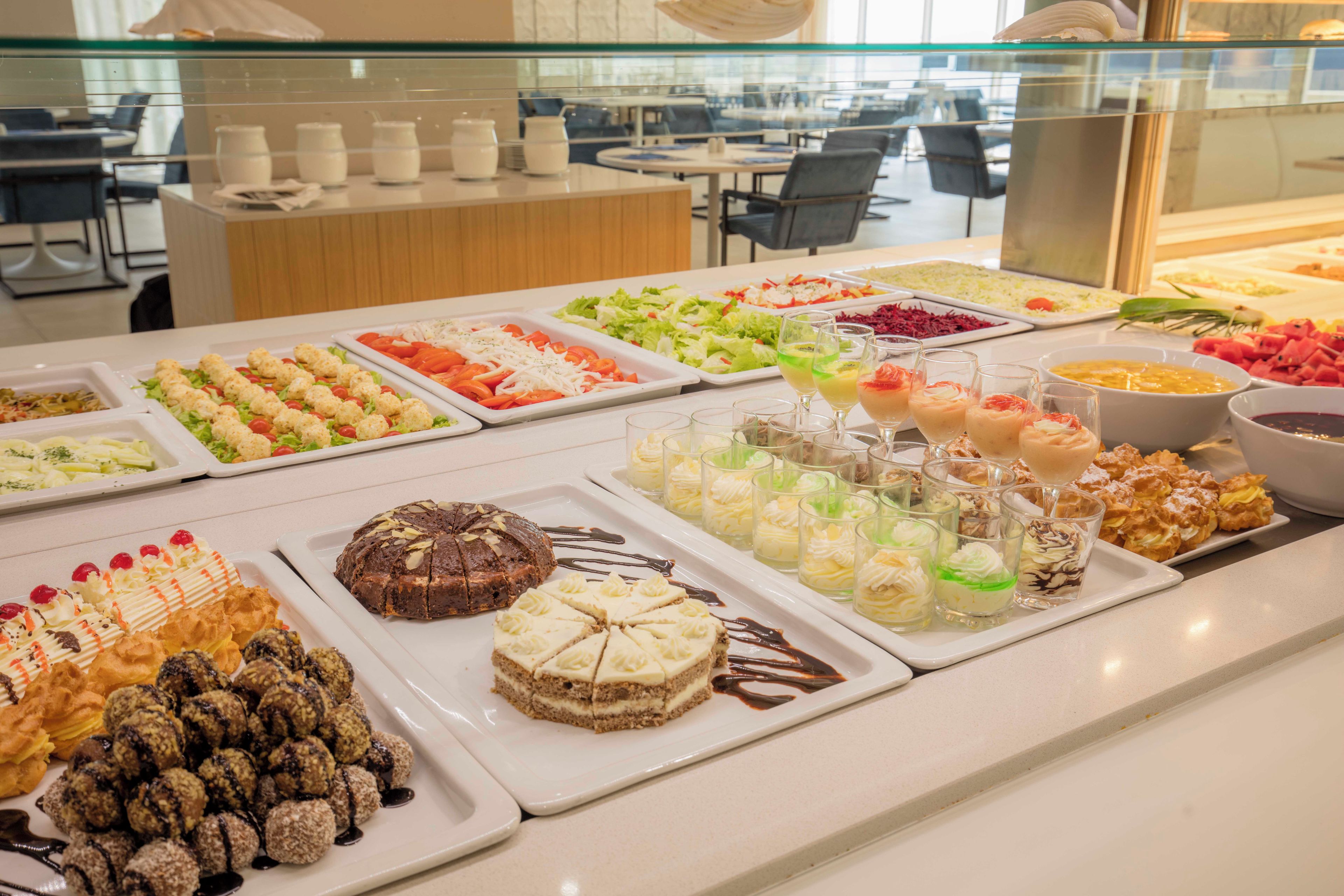 A buffet with various food options including salads, desserts, and beverages.